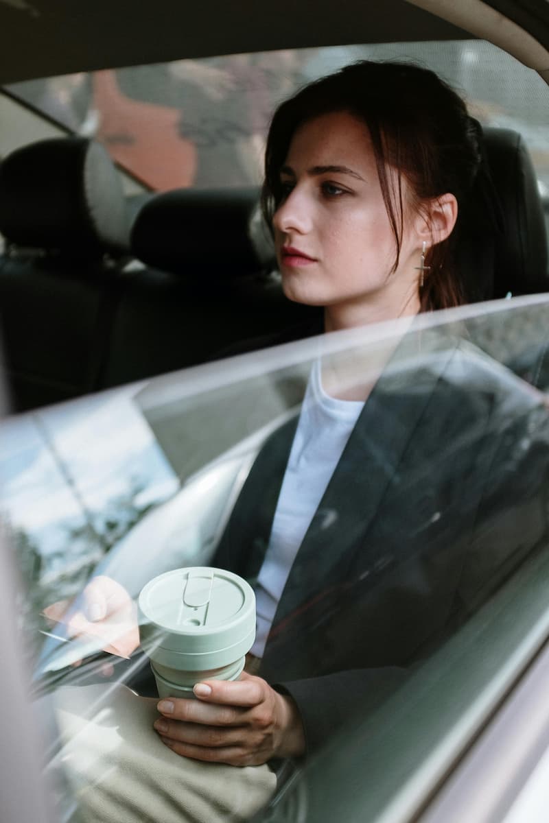 Woman with a coffee in the back of a rideshare